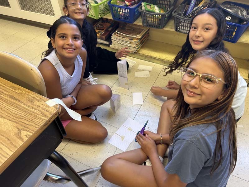 Students smiling at camera, sitting at table.
