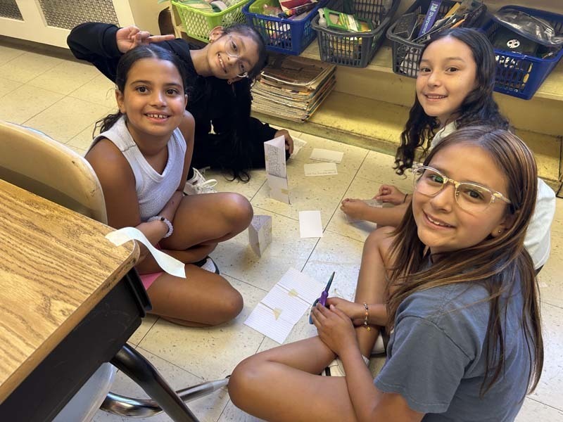 Students smiling at camera, sitting at table.