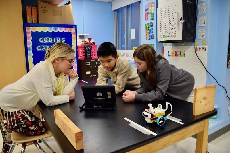 Teacher helping students with project.