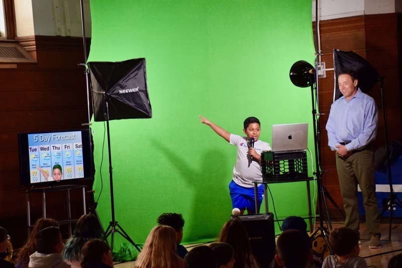 Student standing with meterlgst n front of green screen.