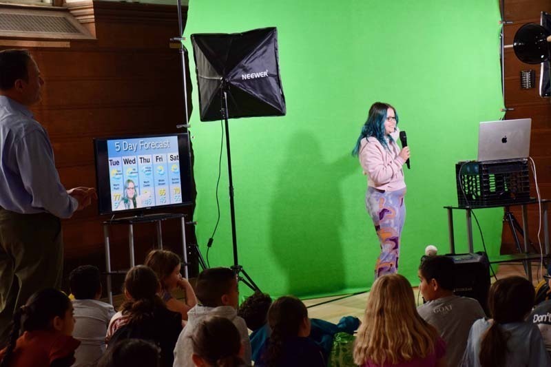 Student standing with meterlgst n front of green screen.