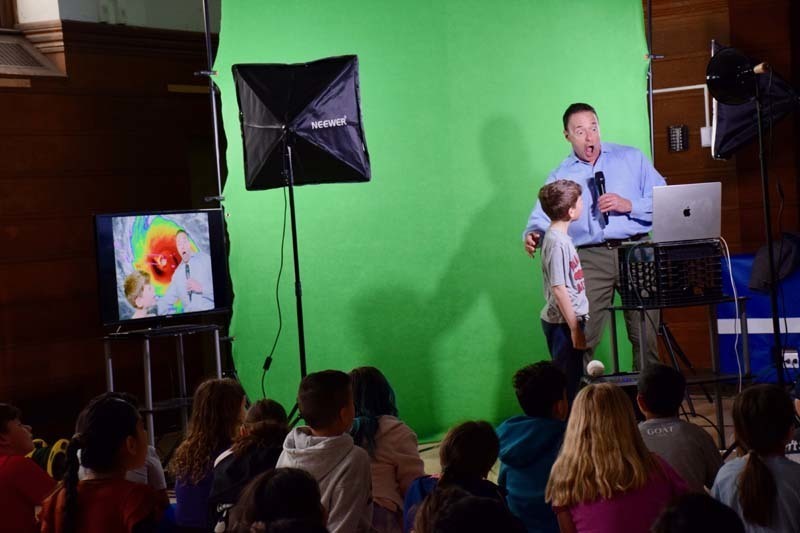 Student standing with meterlgst n front of green screen.