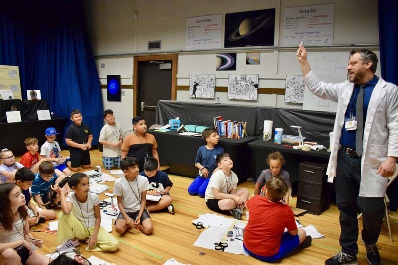 Scientist holding and explaining an object to students.