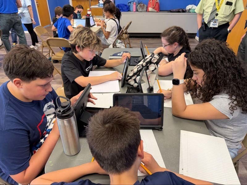 Students sitting at table participatng in challenge.