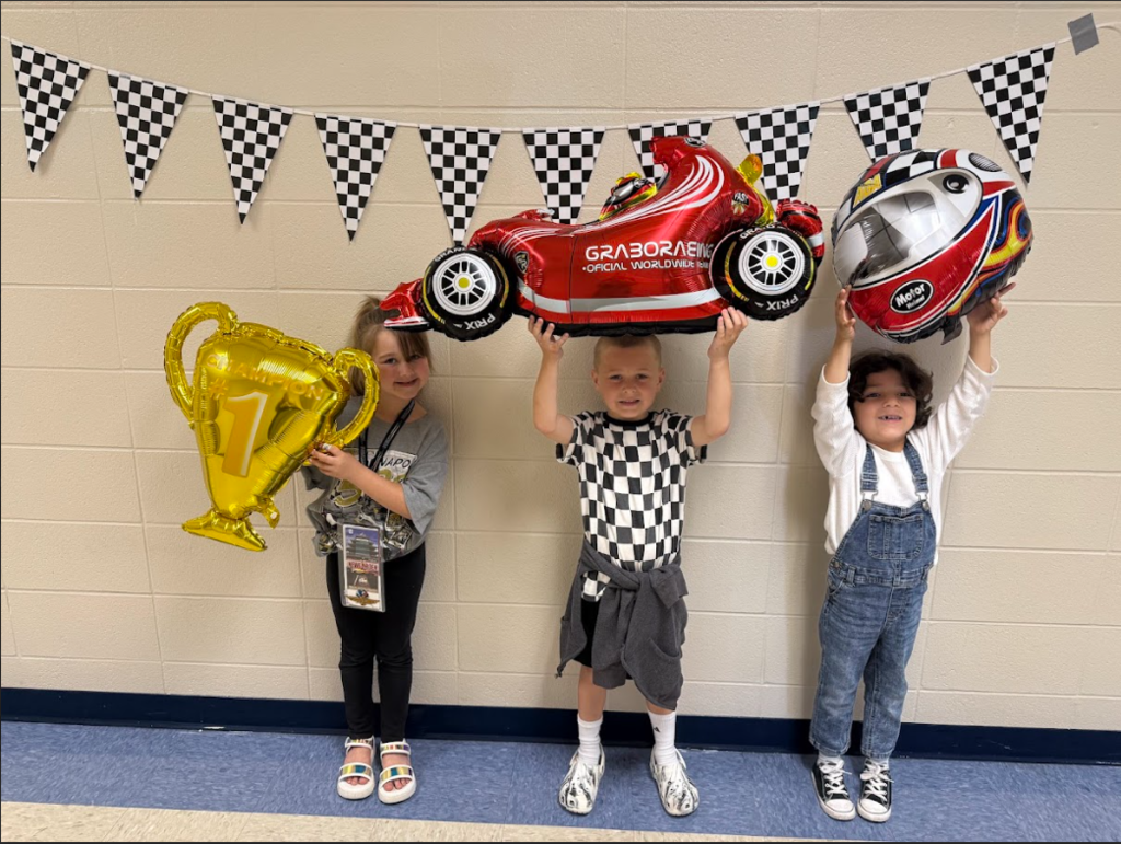 students holding up race themed balloons