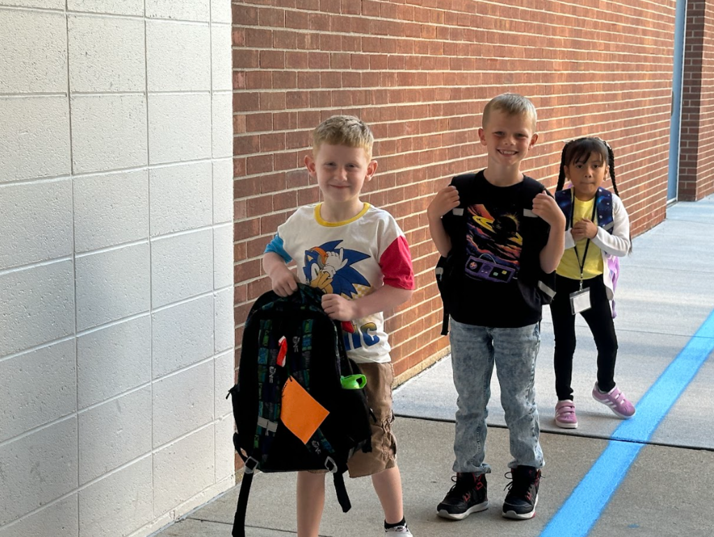 3 students waiting with backpacks