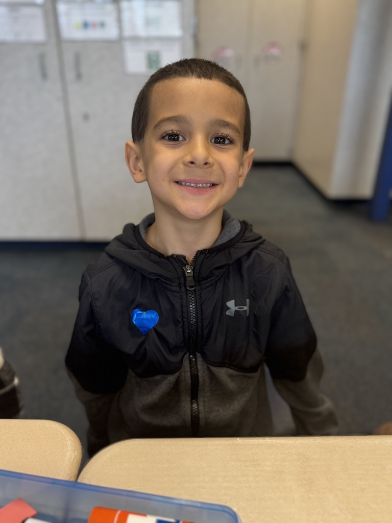 First grade student smiling with a blue heart sticker