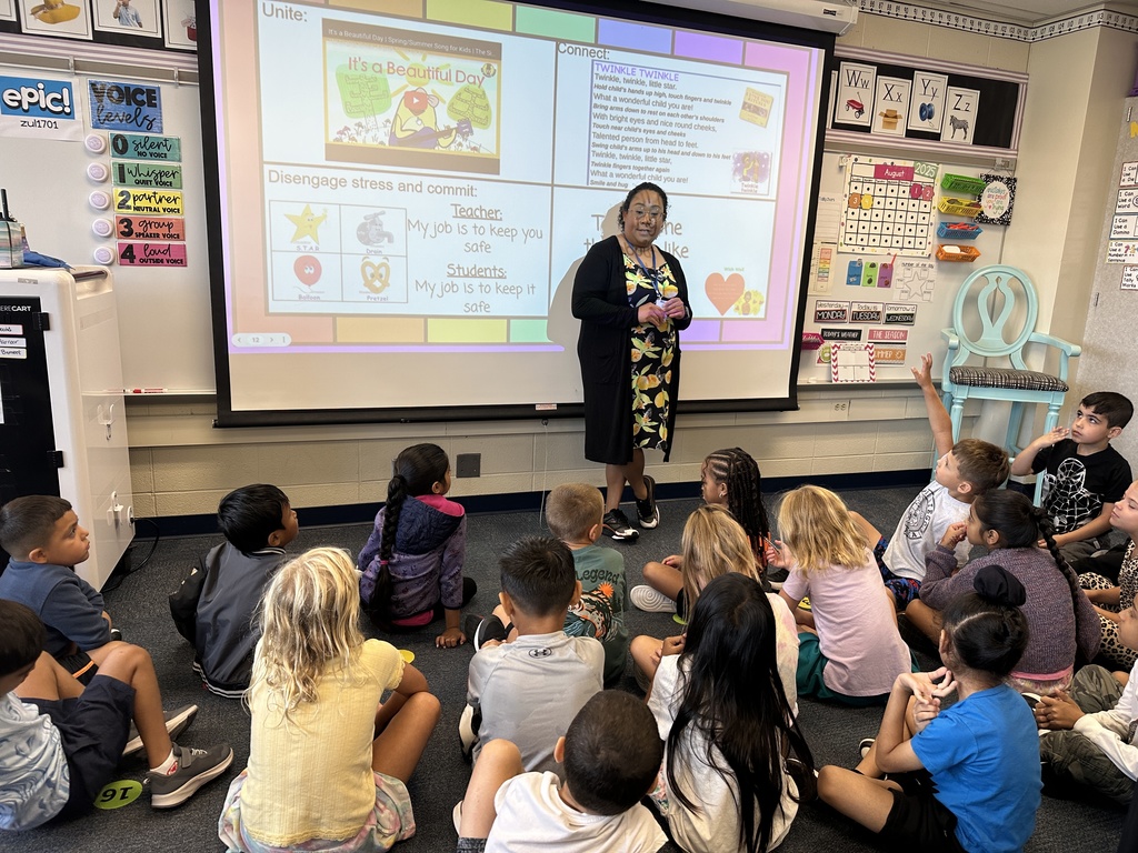 first grade students sitting on carpet learning from teacher