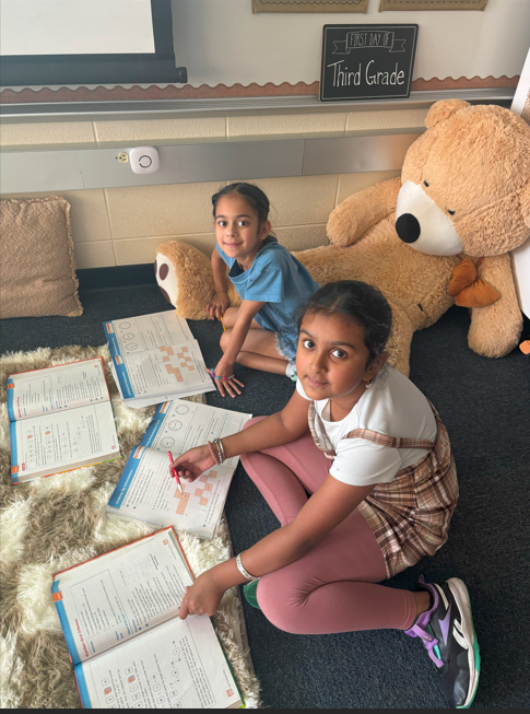 two students doing school work on the floor smiling