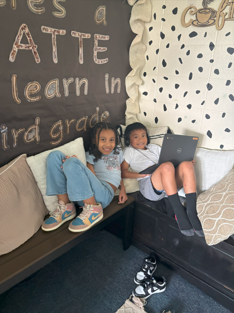 two students doing school work on the floor smiling