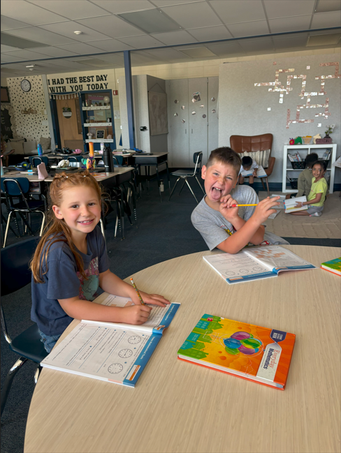 two students doing school work smiling