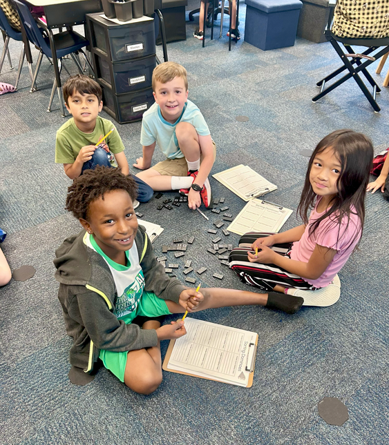 four students working with dominos on the floor