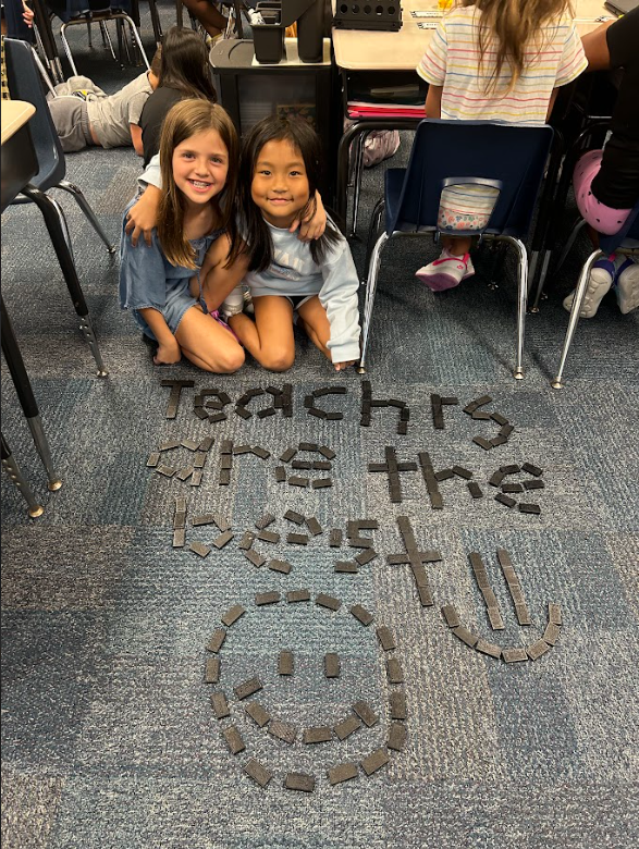 Students sitting on the floor with tiles that spell out Teachers Are The Best