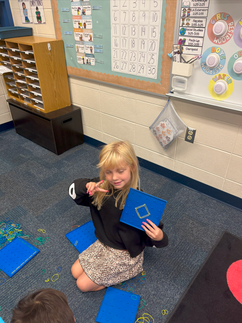 student smiling with geoboard