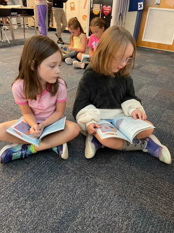 two students reading in partners in the floor