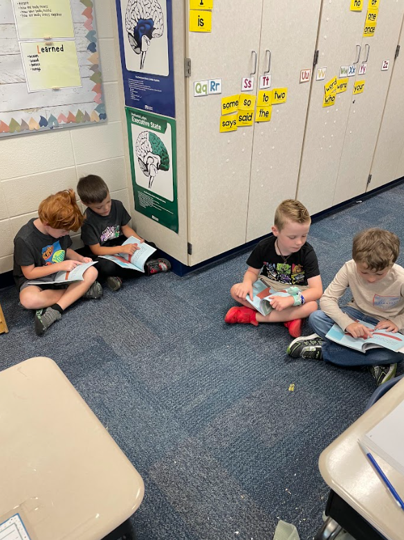 4 students reading in partners on the floor