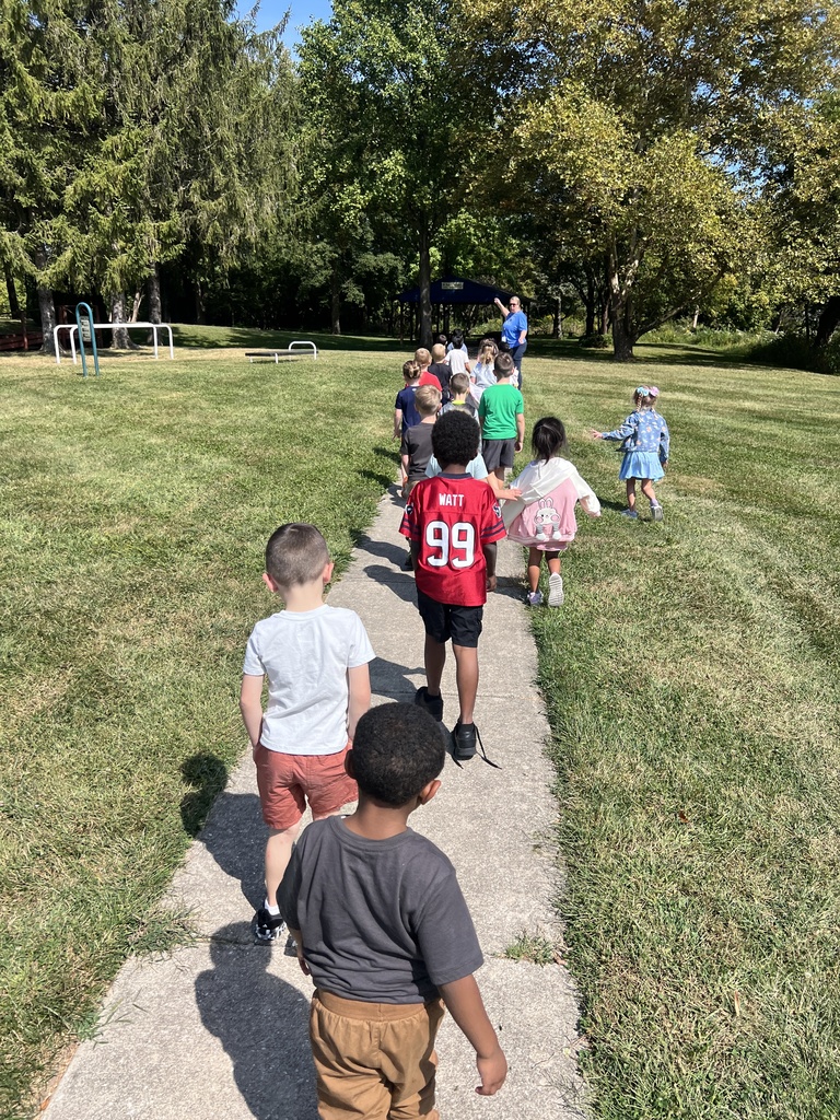 Class of kindergarten students walking along a sidewalk outside