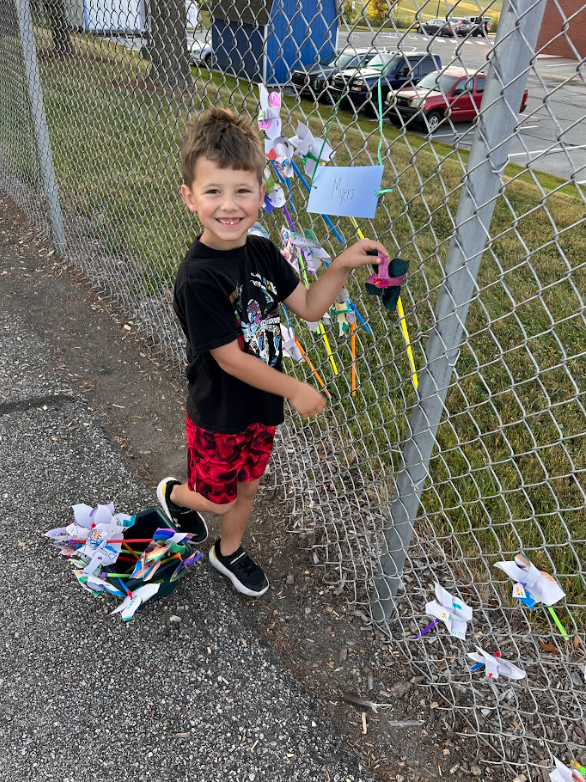 Student putting a pinwheel in the fence