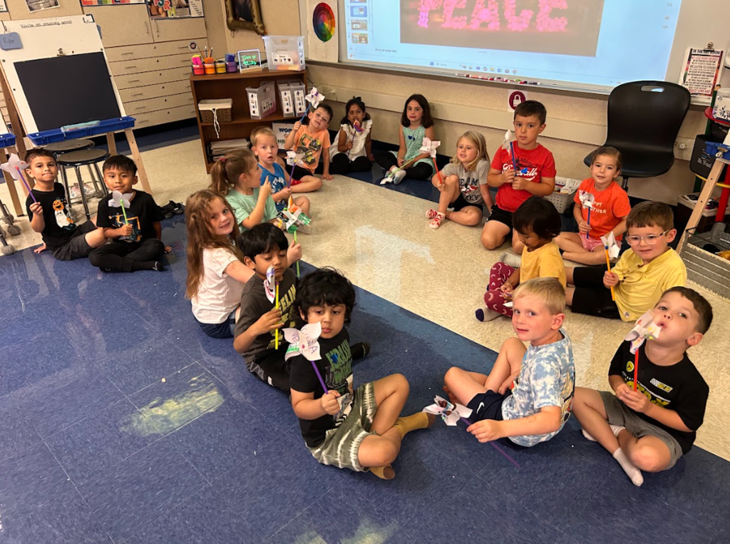 Kindergarten students smiling with the pinwheels they made