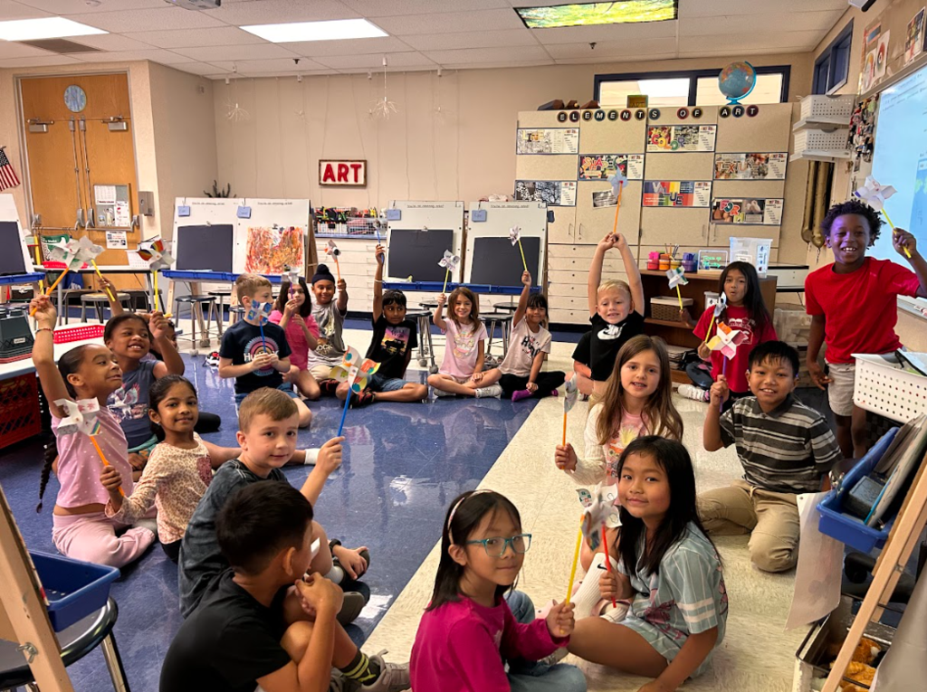 Second grade students smiling with the pinwheels they made