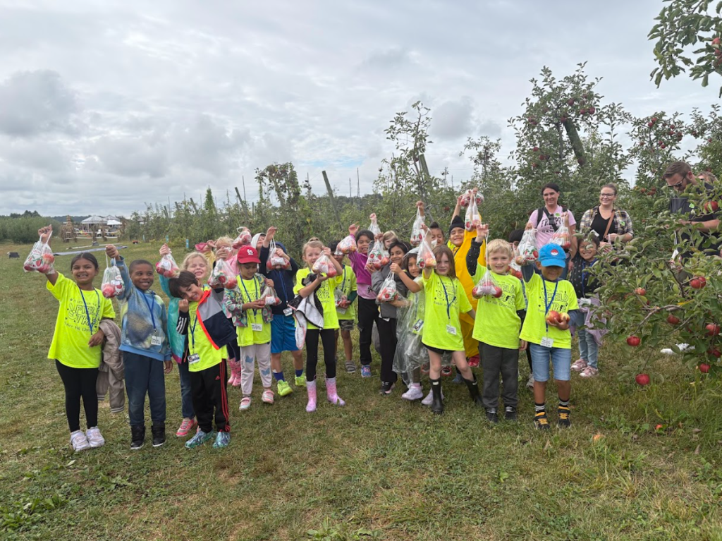 Class of Students holding up their apples they picked on the field trip