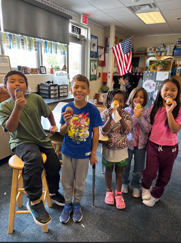 Students holding up potatoes