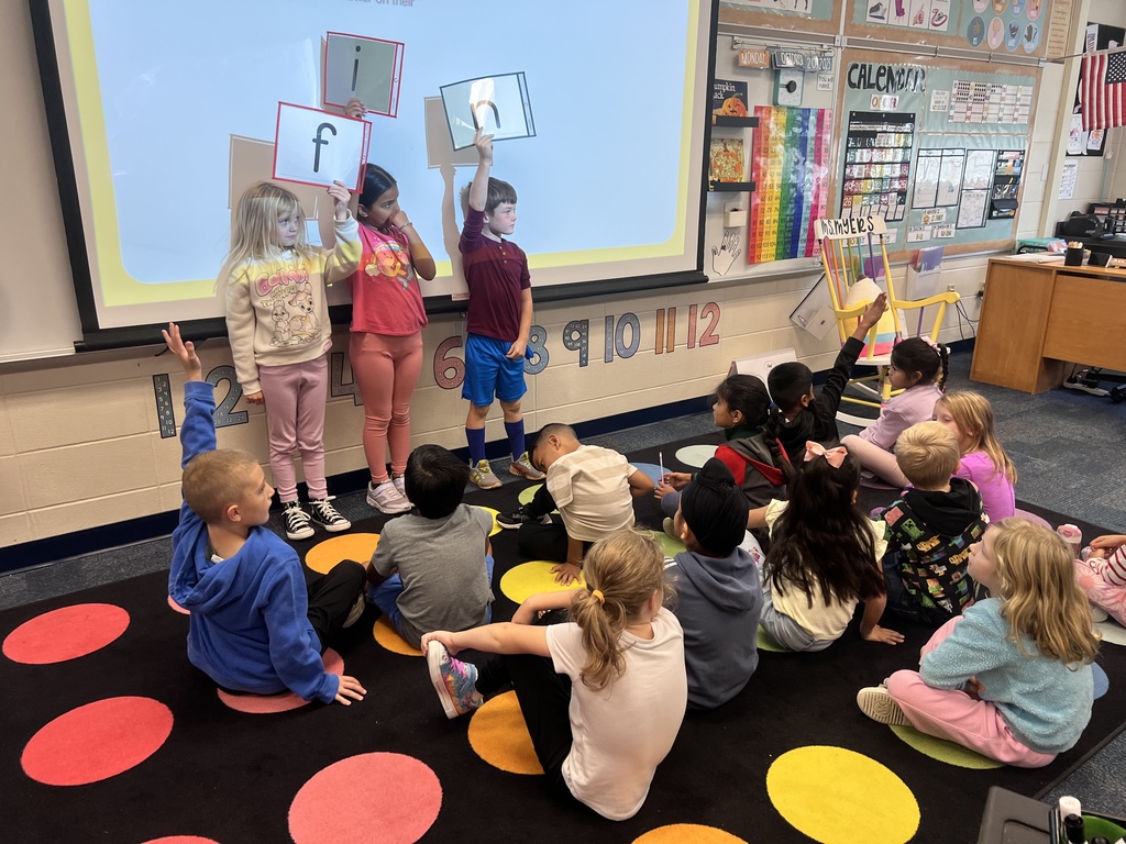 students holding up letter cards working on the magic e rule