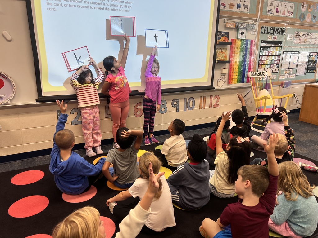 students holding up letter cards working on the magic e rule