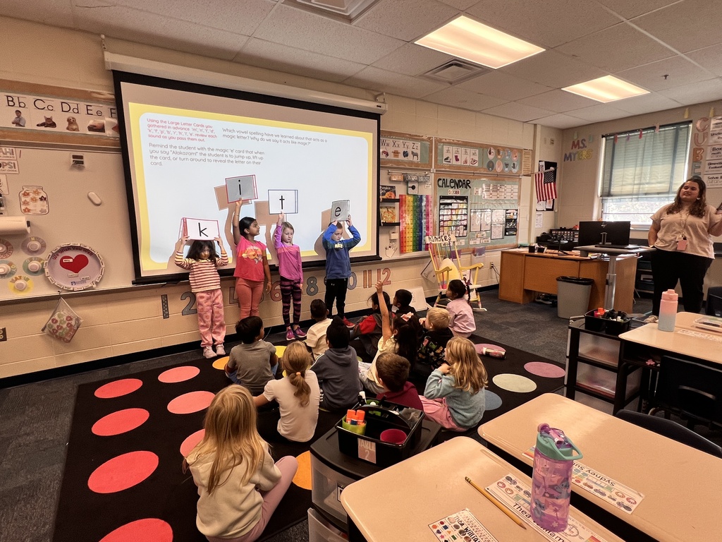 students holding up letter cards working on the magic e rule