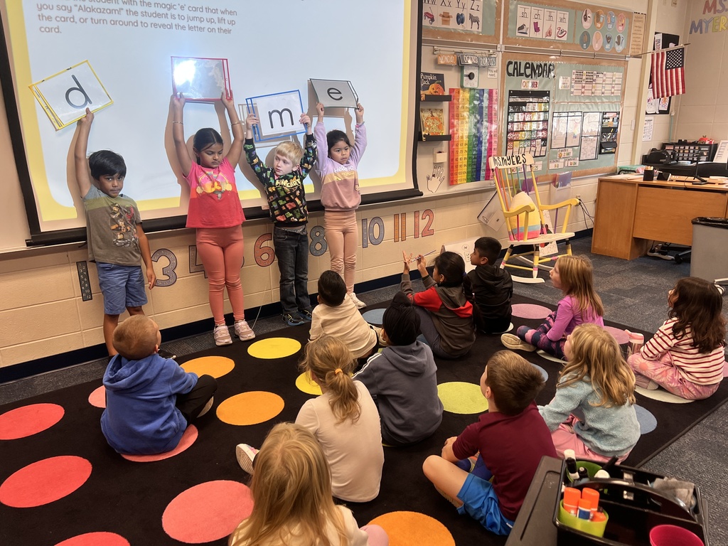 students holding up letter cards working on the magic e rule