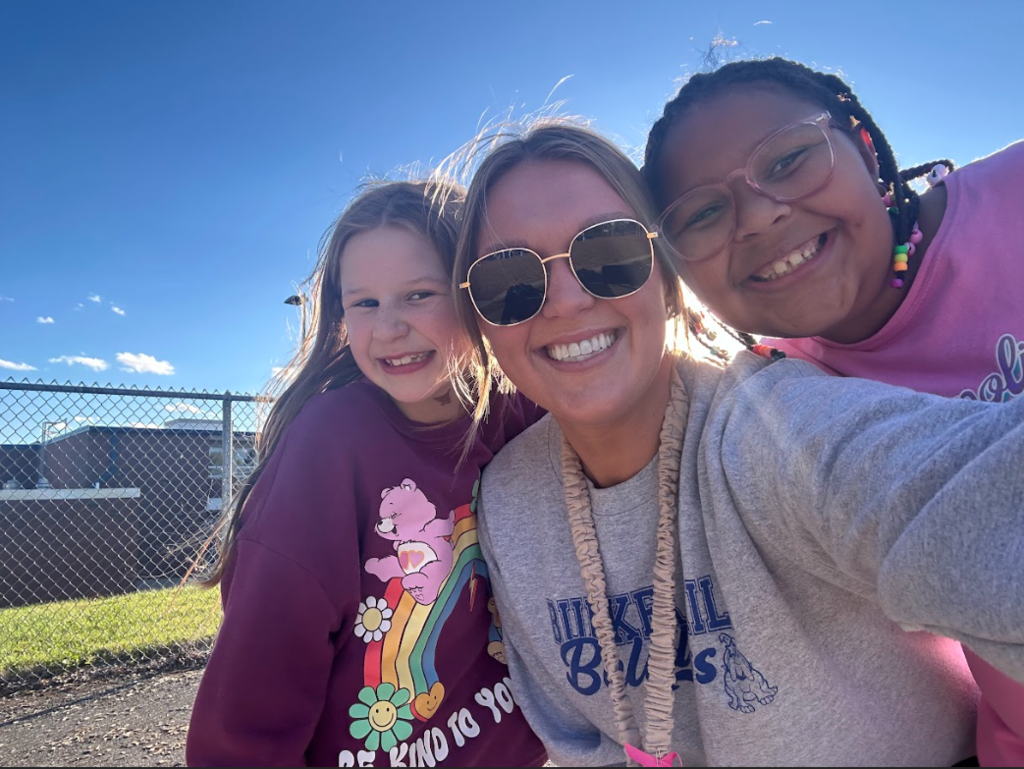 Two students smiling in a selfie with a teacher