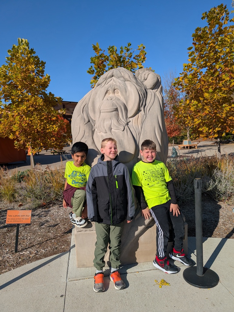 students smiling in front of orangutan statue at the Indy Zoo
