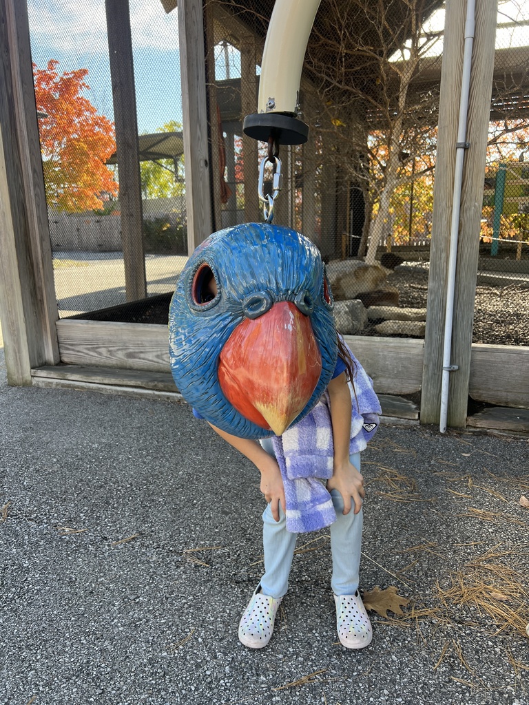 Student behind hanging bird head mask at the Indy Zoo
