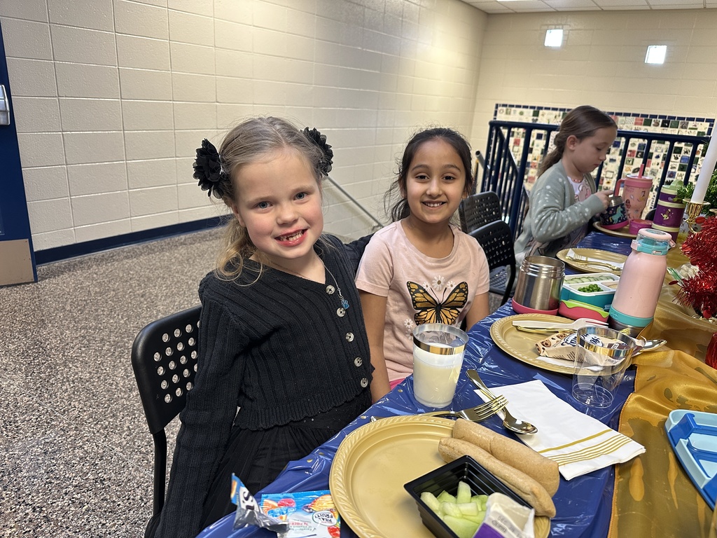 Students at a table eating a lunch with the principal