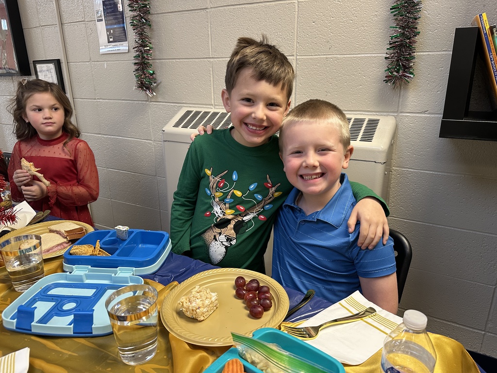 Students at a table eating a lunch with the principal