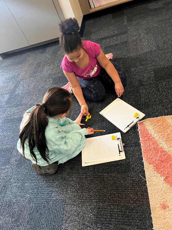 two students working together on the floor