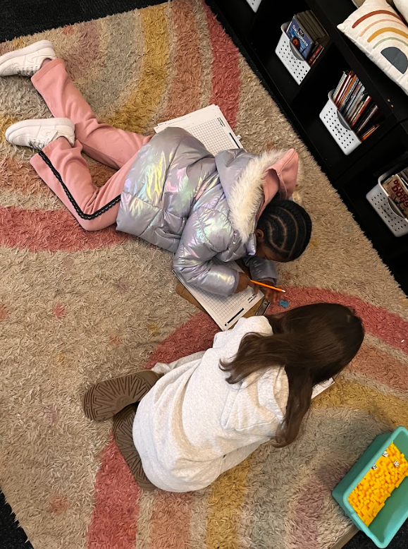 two students working together on the floor