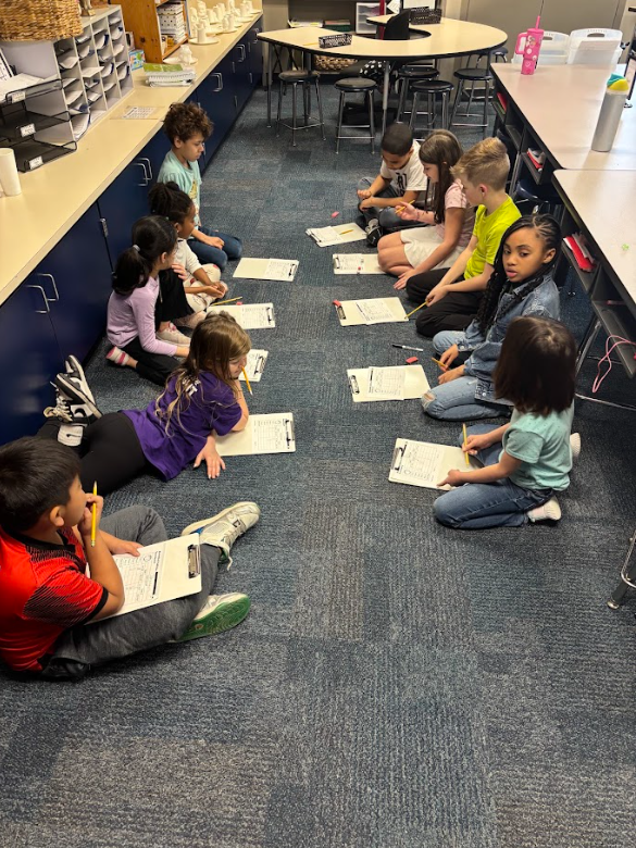 students working together on a paper using clipboards on the floor
