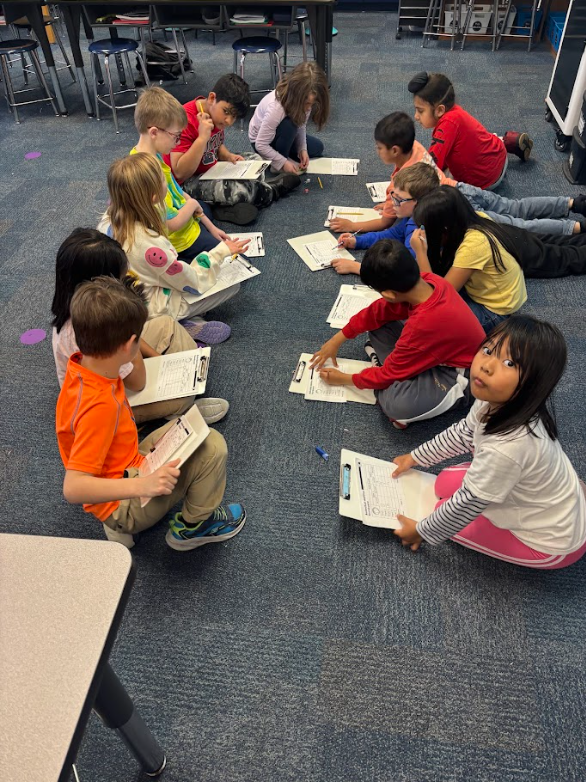 students working together on a paper using clipboards on the floor