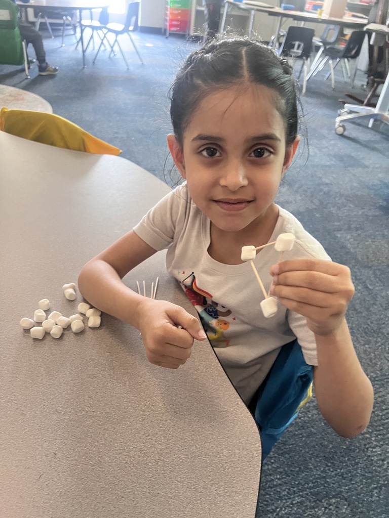 kindergarten student building a shape out of toothpicks and marshmallows 