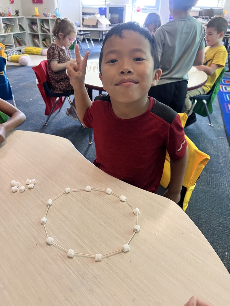 kindergarten student building a shape out of toothpicks and marshmallows 
