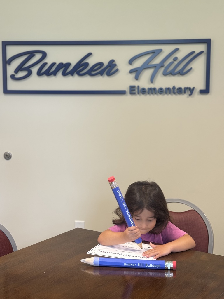 student signing certificate with large pencil