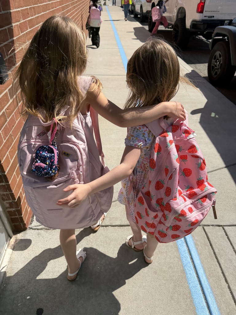 two students walking arm in arm down our sidewalk