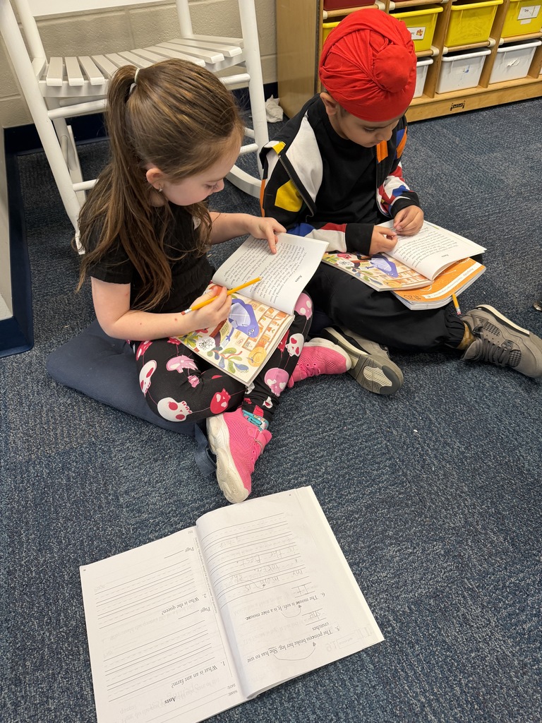 two students reading a book together on the floor