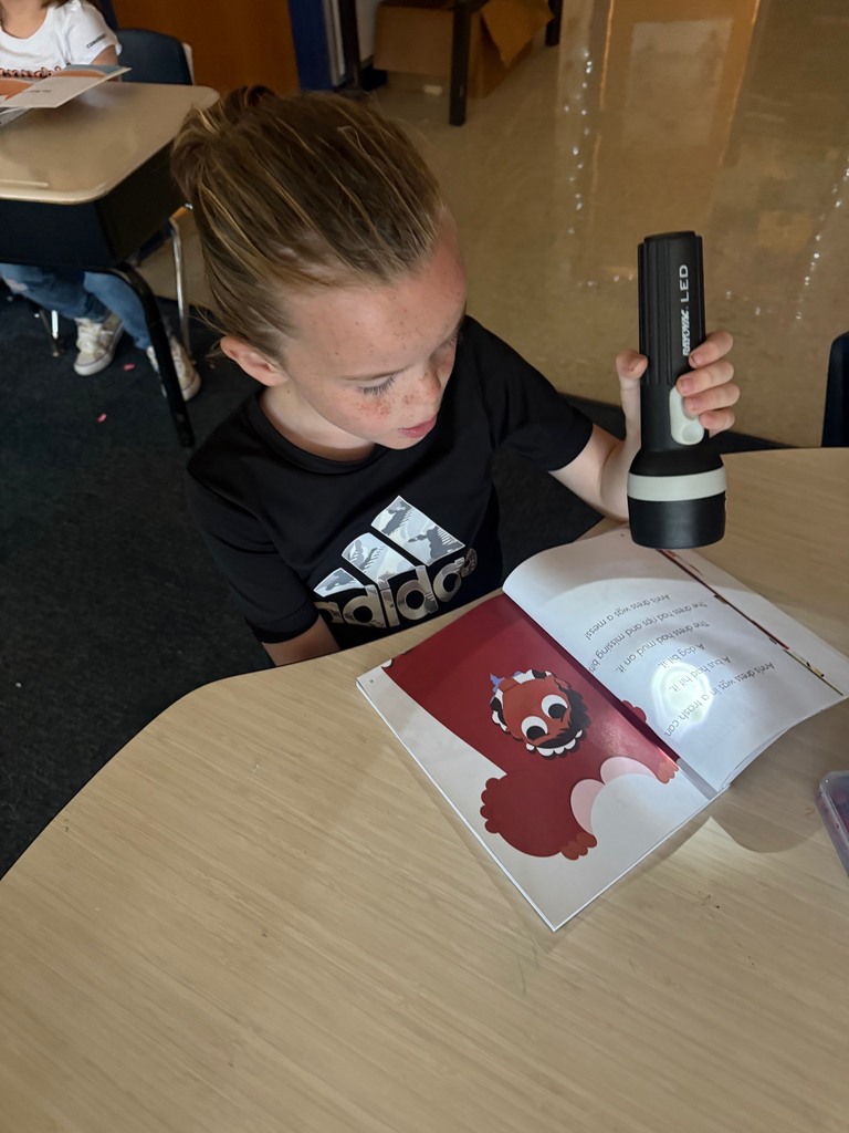 kindergarten student reading with a flashlight