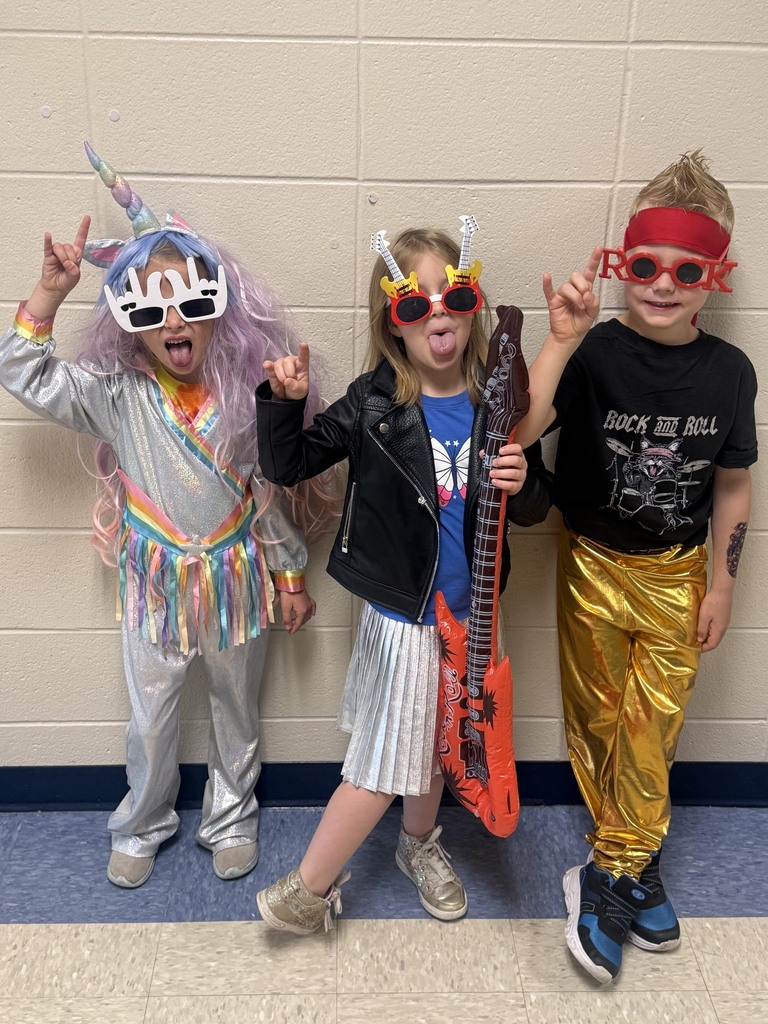 Kindergarten students dressed up for Rockstar Day holding up rock symbols with their hands and sticking out their tongues