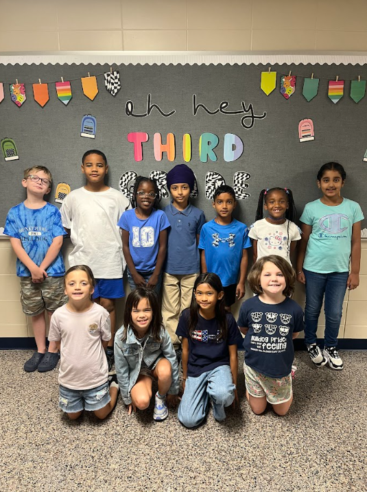 11 students in two rows smiling wearing blue spirit day shirts