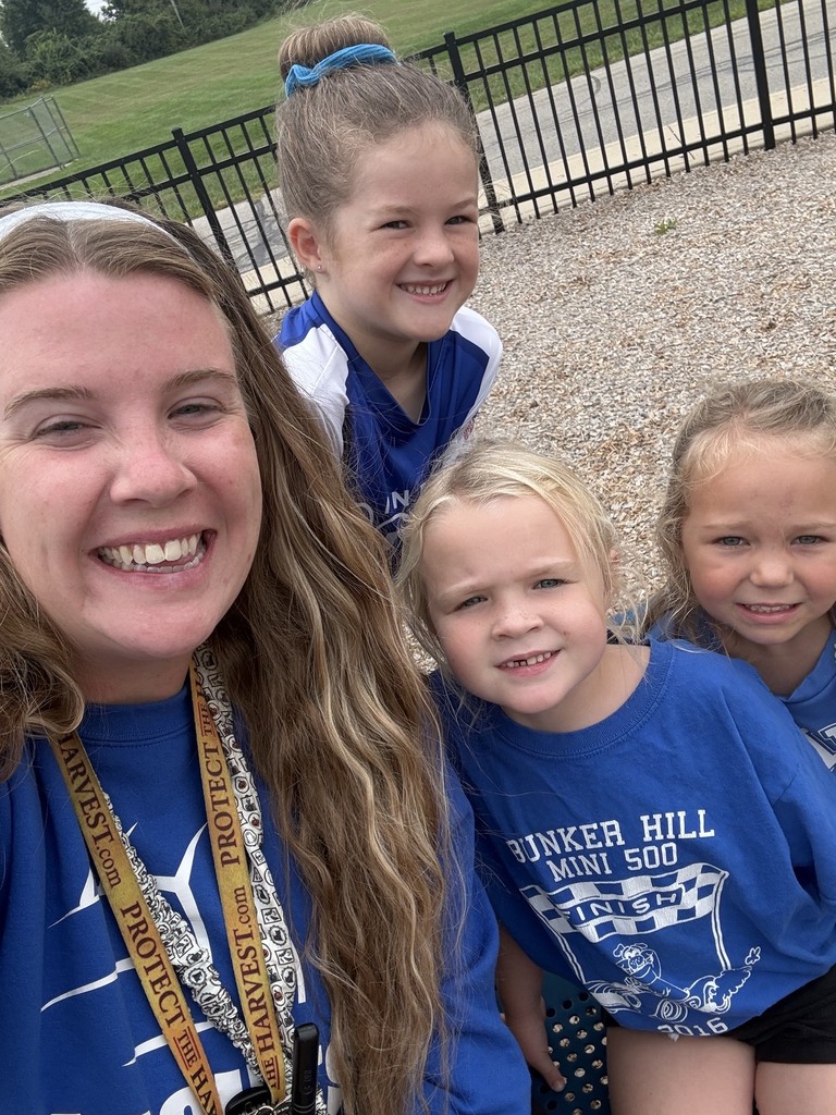 selfie of teacher with three girl students smiling in blue shirts for spirit day