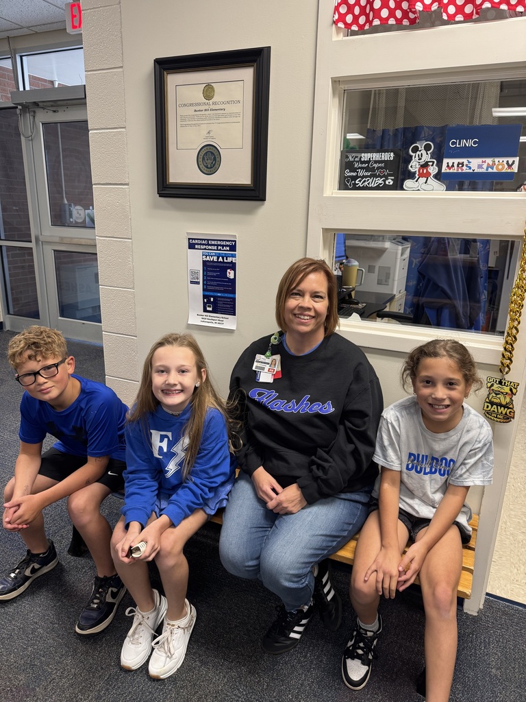 school nurse sitting on a bench with three students all wearing spirit wear smiling