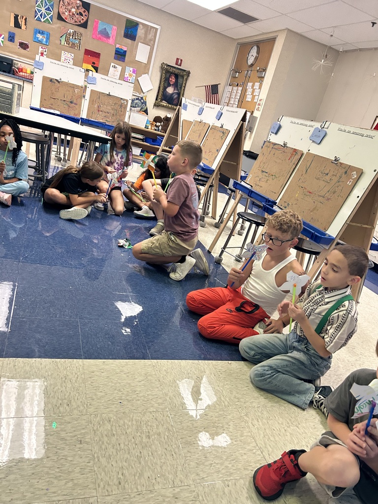 students blowing on the pinwheels that they created in art class